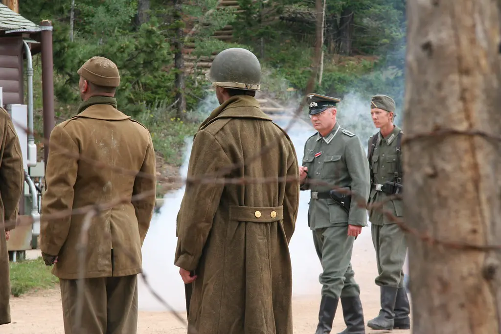 Actors in a WWII scene shot through barbed wire fence