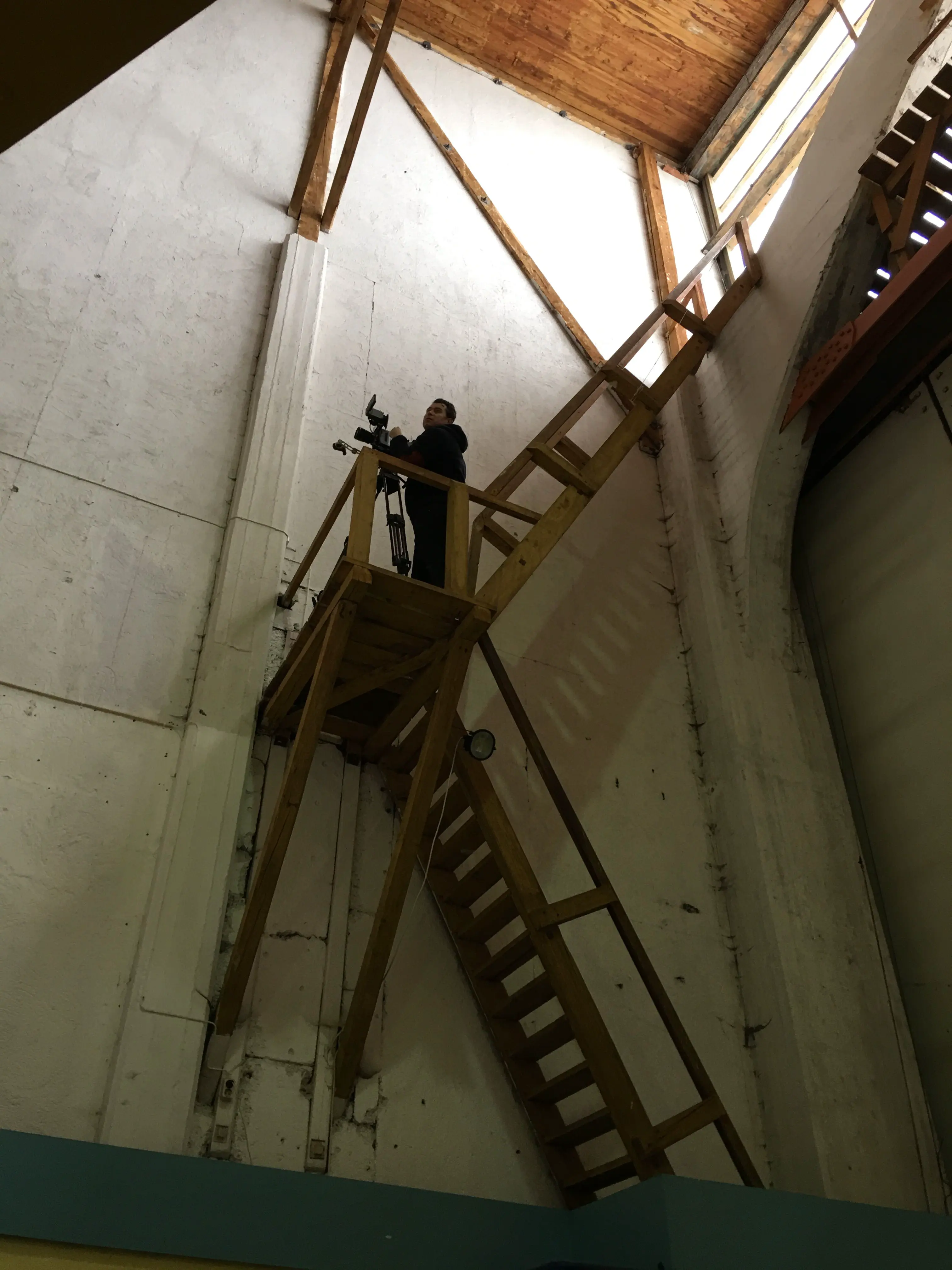 Camera operator on scaffolding high above the floor
