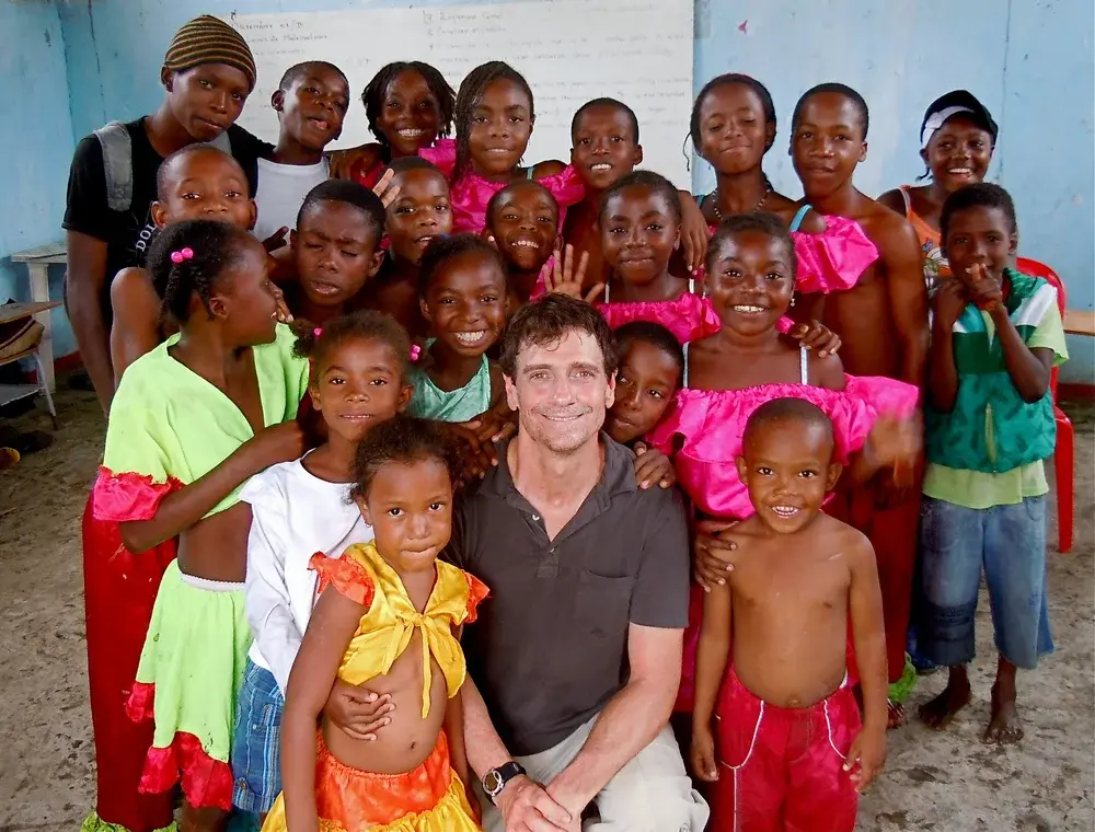 Steve surrounded by children in a classroom