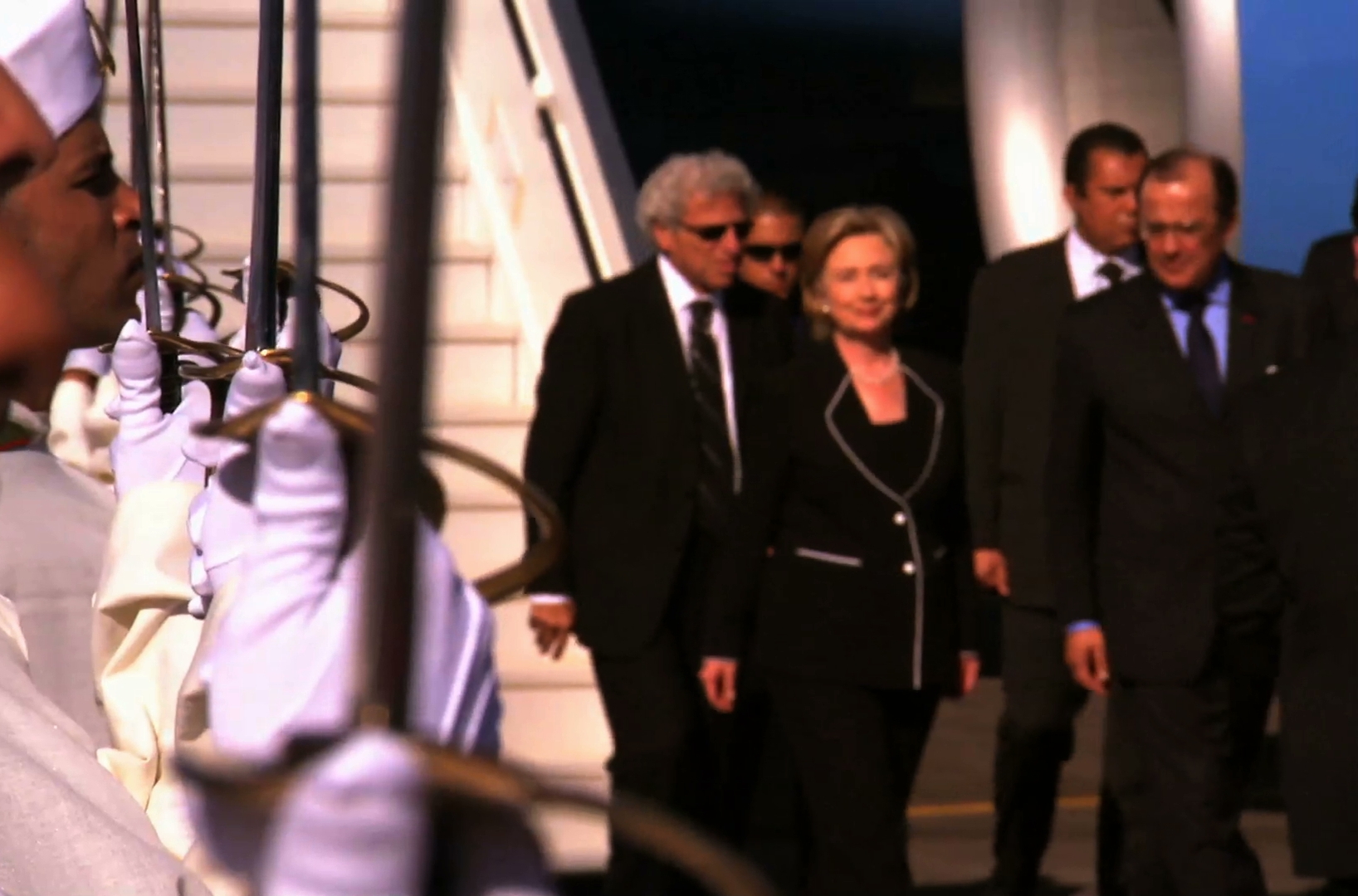 Hillary Clinton walking past a military honor guard